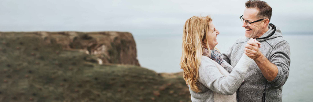 Image showing a romantic senior couple dancing on hill top.